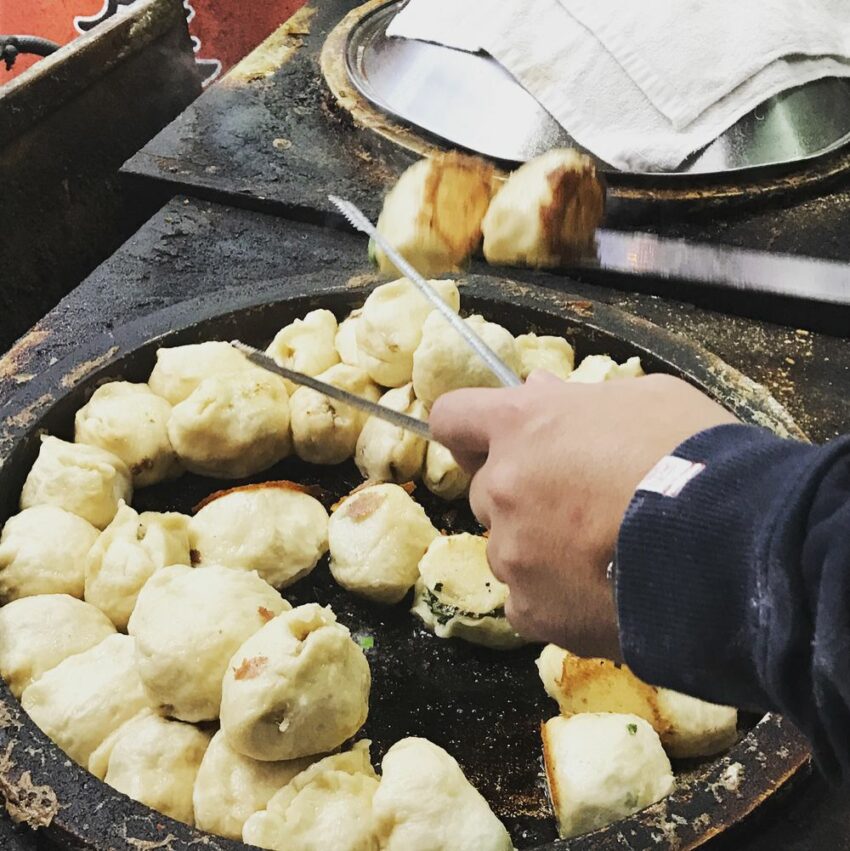 花蓮美食｜在地小吃｜廟口水煎包｜在重慶市場內的廟口水煎包，從以前在城隍廟口前到現在還是大排長龍，只要起鍋就常常被秒殺。廟口水煎包有韭菜、高麗菜兩種口味都是店家現包現煎的，剛起鍋的水煎包冒著熱氣，底部煎的有點焦脆，一口咬下薄度適中的外皮，包裹著高麗菜肉餡，能吃到蔬菜的清甜，搭配特製醬油辣椒真的超級對味！