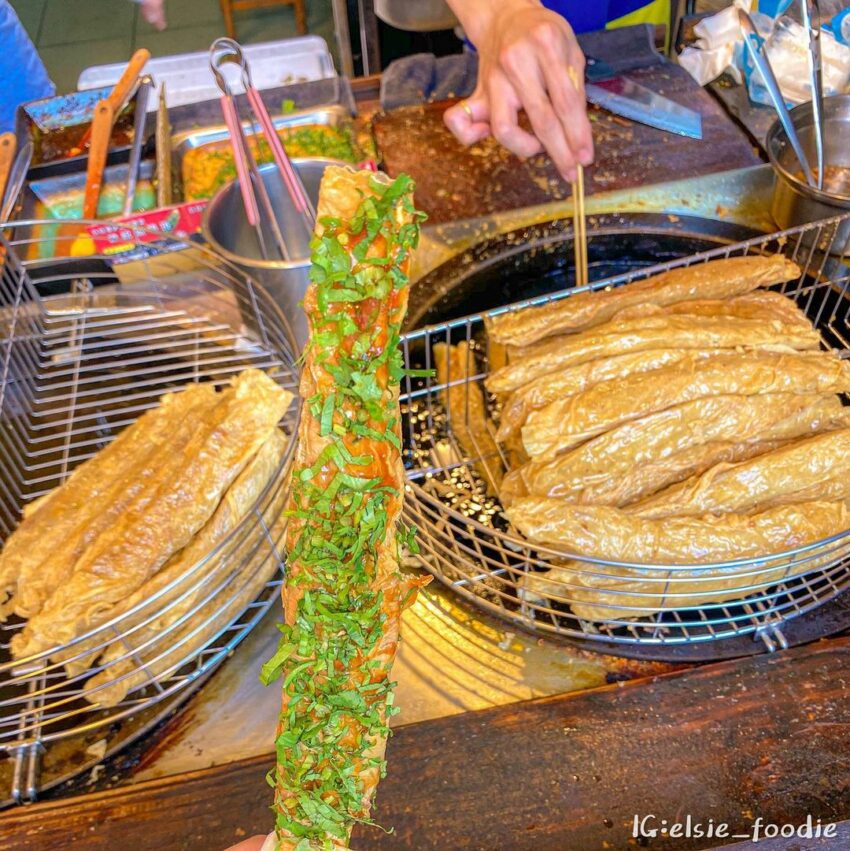  日月潭美食｜必吃特色小吃，總統魚酥捲位於「三豎一橫」街道中，三豎的中間巷子裡，魚酥捲外皮為薄薄的腐皮，裹著用總統魚做的新鮮魚漿，現點現炸，外皮金黃酥脆，內餡著冒著熱氣，有著魚漿的鮮甜與Q彈口感，串上竹籤再淋上特製醬汁和香菜，方便拿著邊吃邊欣賞日月潭美景。